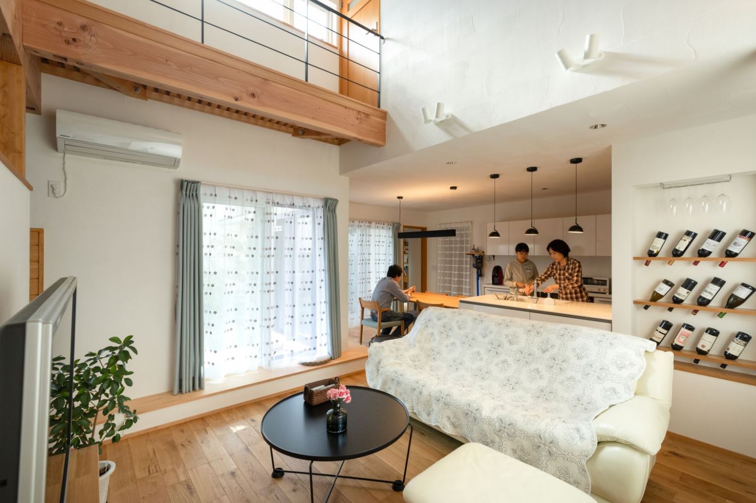 アイジースタイルハウス【収納力、自然素材、間取り】天然木と漆喰を惜しみなく使ったLDK。大きな吹抜けがあっても、調湿+高気密高断熱性能により、冷暖房効率を逃がさない。ニッチのワインコレクションがナチュラルな空間のアクセントに