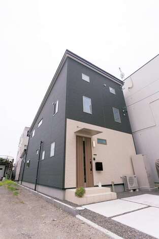 ファサードはシックなツートンカラーに。勾配のついた屋根に太陽光発電パネルを載せたZEH仕様