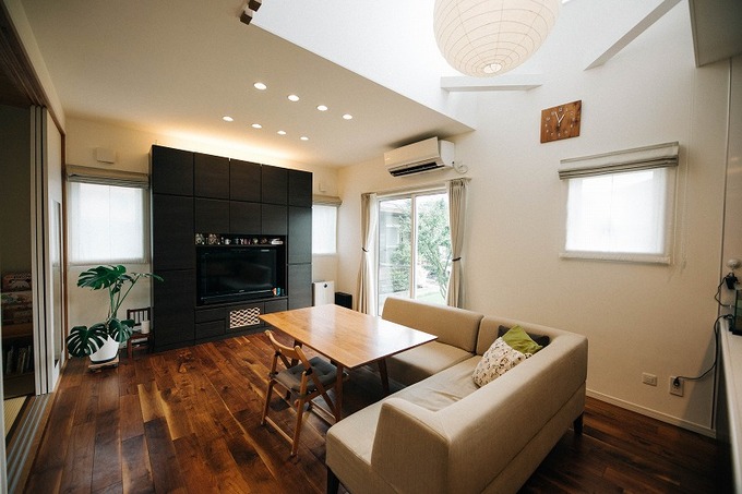 モダンなデザインのリビングルーム。大きな窓や吹き抜けから自然光が差し込み、明るく開放的な空間が広がる。シンプルでスタイリッシュなインテリアが映えるようなシックなテイストに統一。