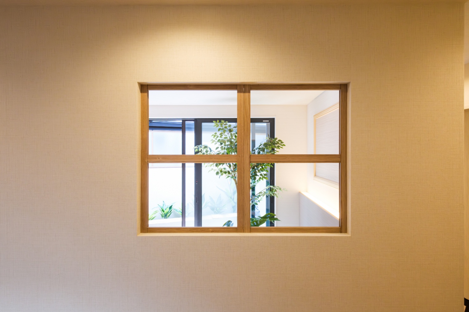 新栄建設｜寝室に設けられた四角い室内窓で、廊下からも外の景色が望められる。木製の窓枠が暖かみを持ち、部屋に自然なアクセントを加えている。