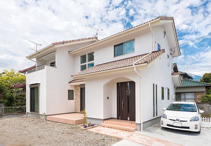 陶器瓦と塗り壁がナチュラルな雰囲気の外観。 吹き抜けの上部にある四つの窓が、デザイン的にもアクセントになっている