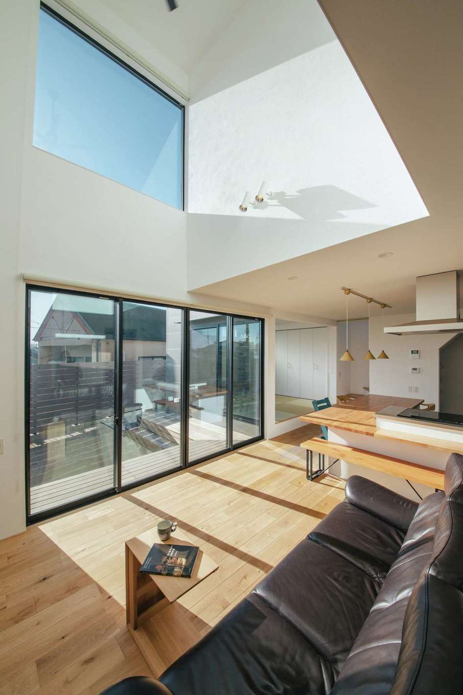  ソラマド浜松【デザイン住宅、子育て、間取り】吹き抜けの高窓、そして庭へと視線が抜けていくLDKは開放感たっぷり。足触りが気持ちいい床は無垢のナラ材で、年月の経過とともに飴色に変化していく