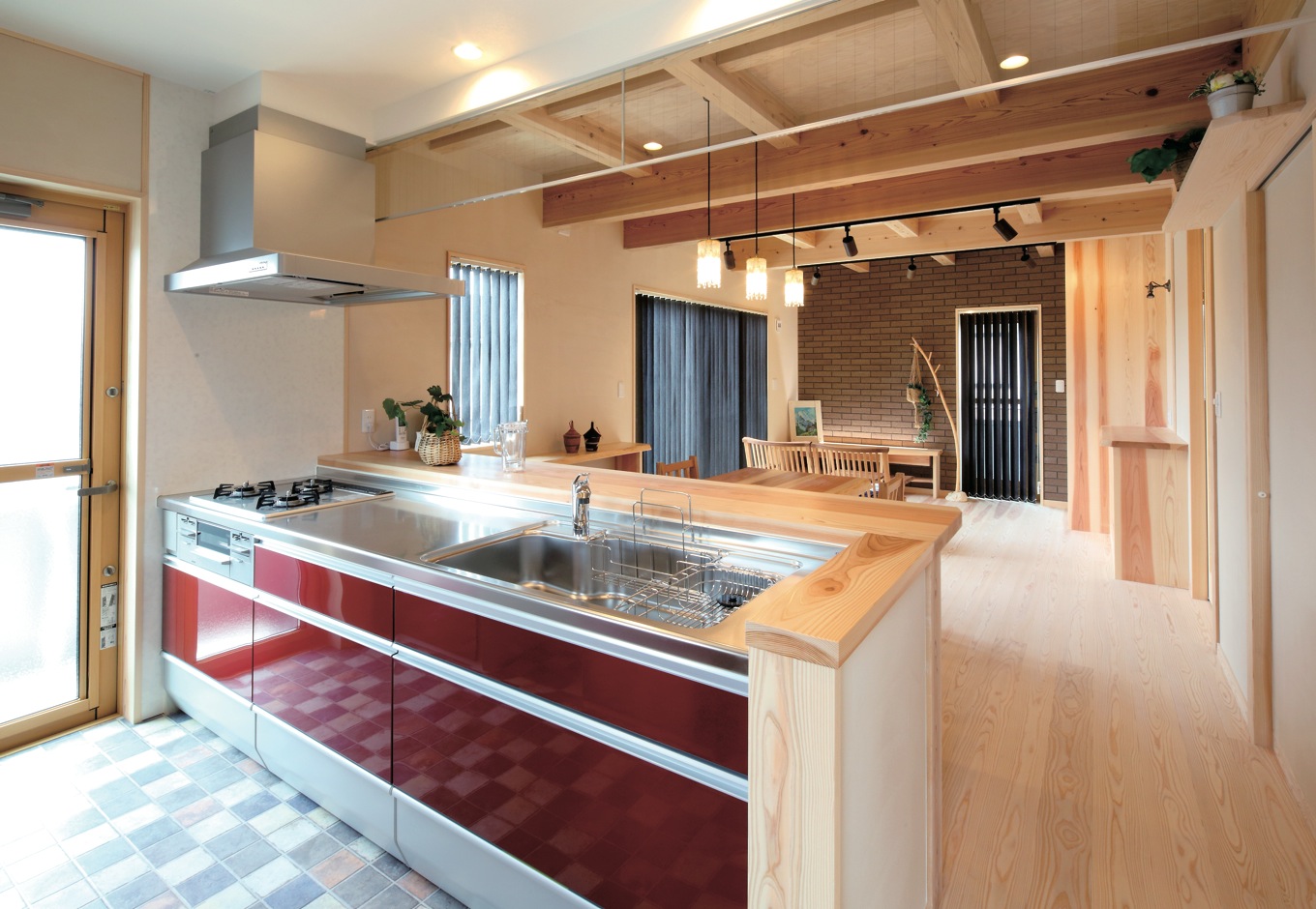 アクトホーム【自然素材、省エネ、間取り】ワインレッドのキッチンやアジアン調のエッセンスをブレンドしたリビングなど、奥さまの要望が随所にちりばめられた。キッチンを中心に洗たく・洗面・浴室の水回りと、物干し場となるバルコニーを連続させ、家事効率を高めている