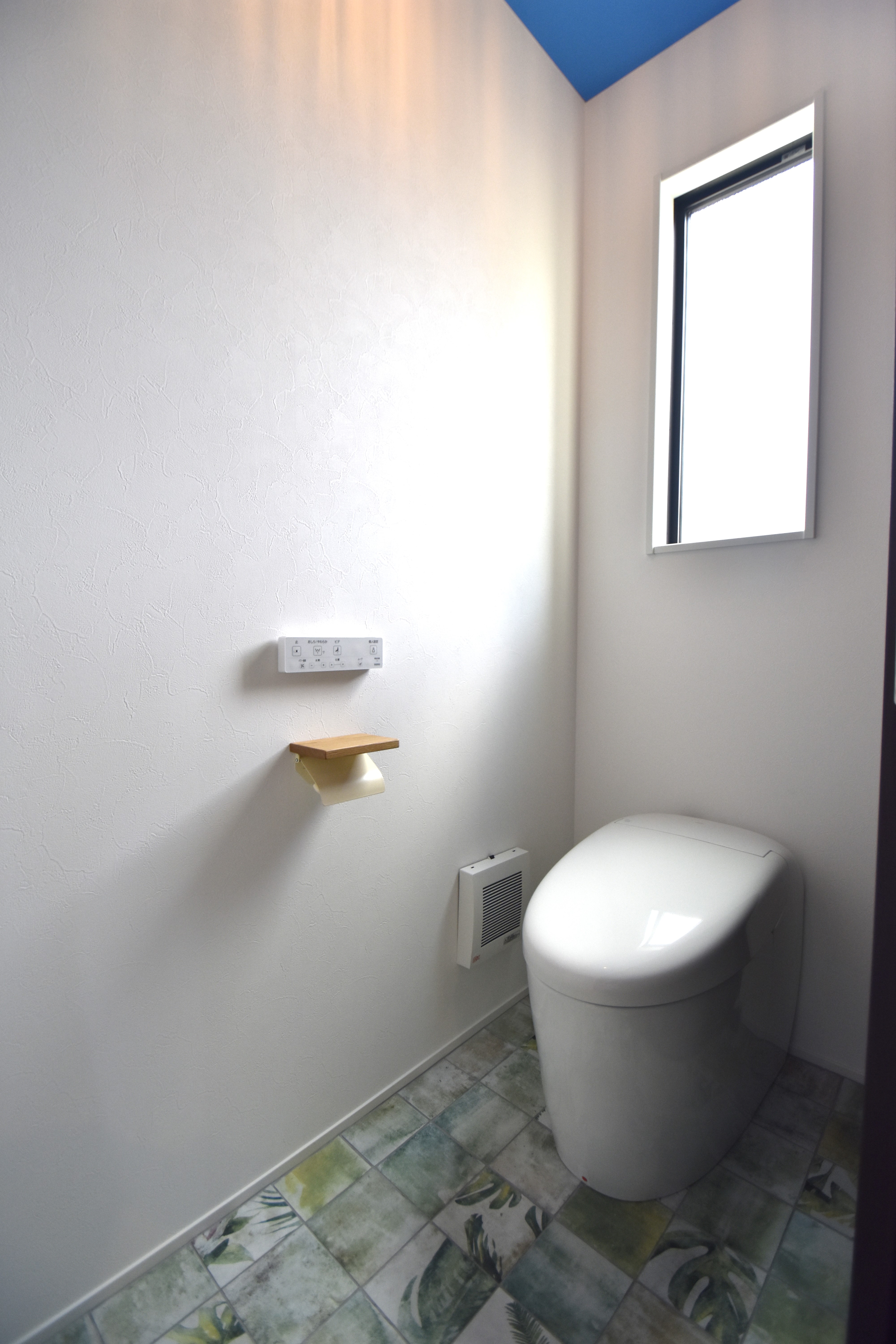 カクニシビルダー｜1階トイレは、天井の鮮やかなブルーのクロスと、オシャレなタイルが印象的。オーナー様のセンスが感じられる。