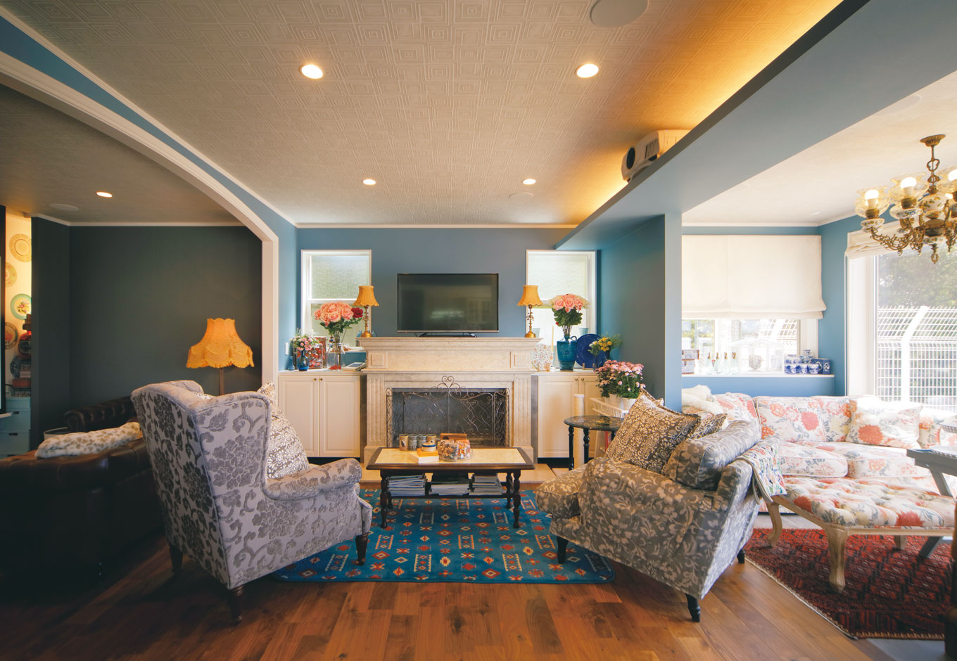 幹工務店【デザイン住宅、輸入住宅、インテリア】リビングはサンルーム・暖炉コーナー・シアターコーナーの3つに分かれ、それぞれにソファセットが置かれている。床はブラックウォルナット。バイオエタノール暖炉に大理石のマントルピースを配置した。照明をシンメトリーに飾ったり、花瓶などの小物は3つ同じものを並べて配置したりと、奥さまのコーディネート術はまさにプロ級