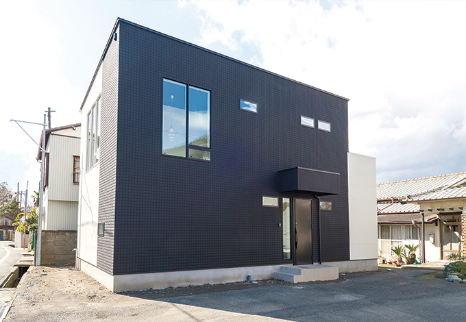 シンプルなキューブ型の外観。内観と同じく、外壁も黒と白にこだわった。南東の窓ガラスにポールセンの照明が美しく浮かび上がる