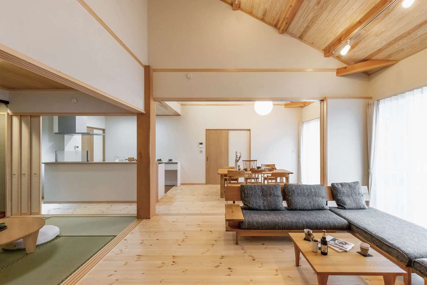 住まいるコーポレーション【二世帯住宅、自然素材、平屋】勾配天井のリビング。床には厚さ30mmの松の天然木、壁には珪藻土を採用。冬でも天然木の床が保温性を発揮して、足元を暖かく保つ。引き戸を閉めれば、それぞれのスペースを分けて使うことができる