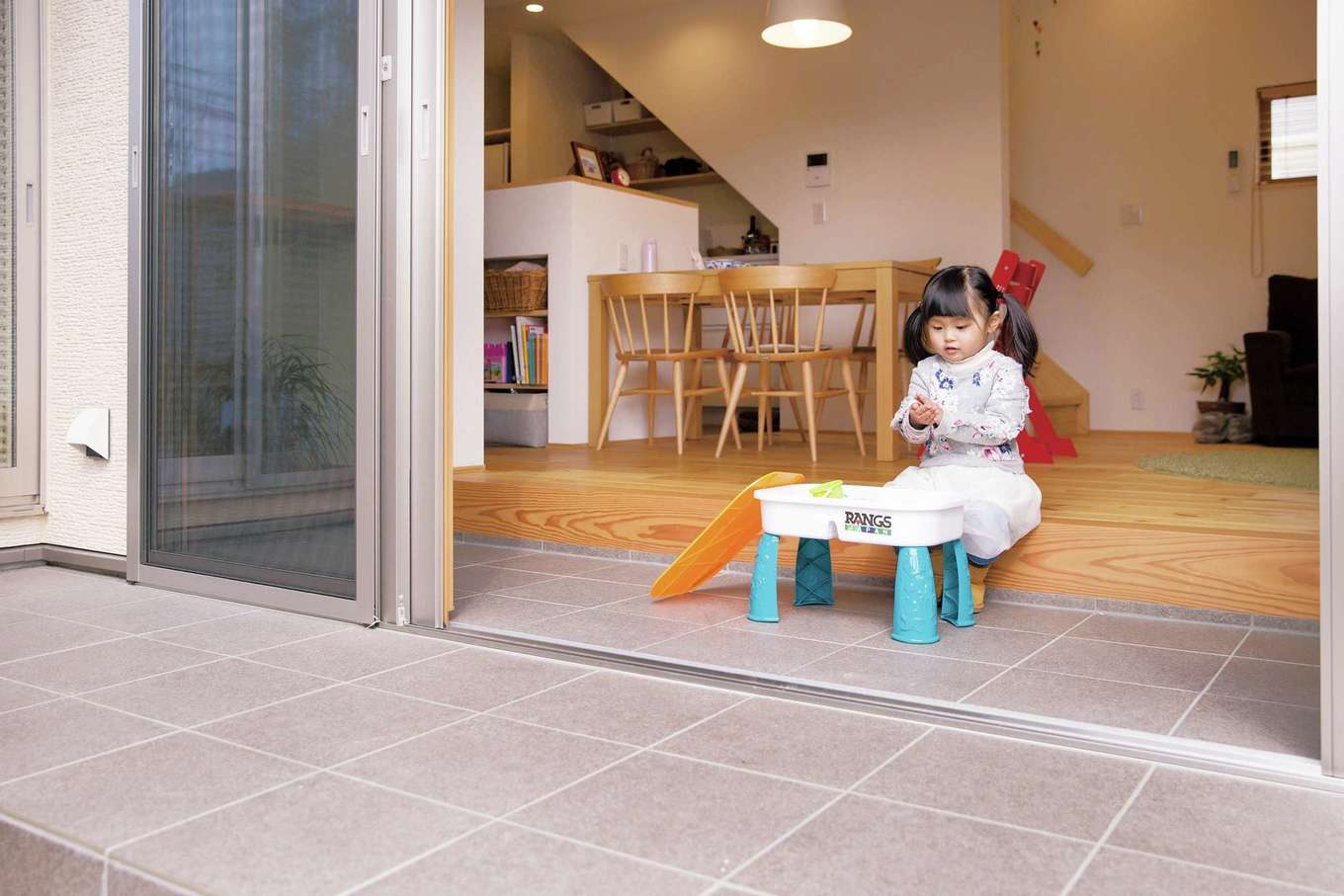 SEVEN HOUSE/セブンハウス【デザイン住宅、子育て、自然素材】この家の最大の特徴である土間は、内のリビングと外の庭の中間に位置。天候の悪い日や、寒さや暑さのひどい日でも小さな子どもが心置きなく遊ぶことができて、子育てママにとってはとても安心だ。庭で遊ぶ様子をキッチンなどから手に取るように把握できる配置も素晴らしい