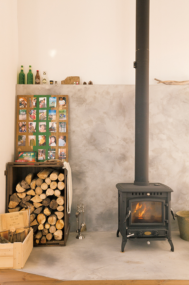 富士ホームズデザイン【デザイン住宅、子育て、インテリア】『富士ホームズデザイン』の事務所に薪ストーブがあり、その暖かさにひかれて導入。ありがちなレンガ壁でなく、モルタル仕上げにしたところ がSさん流だ。墨を混ぜて自然なムラを出した『富士ホームズデザイン』 のアイデアが光る