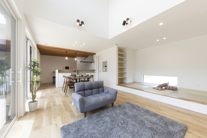 開放的なリビングダイニングキッチンの空間。モダンなチェアと広々としたスペースが、家族での時間を豊かにするデザインである。床は明るい木目調で、ナチュラルな雰囲気を演出している。