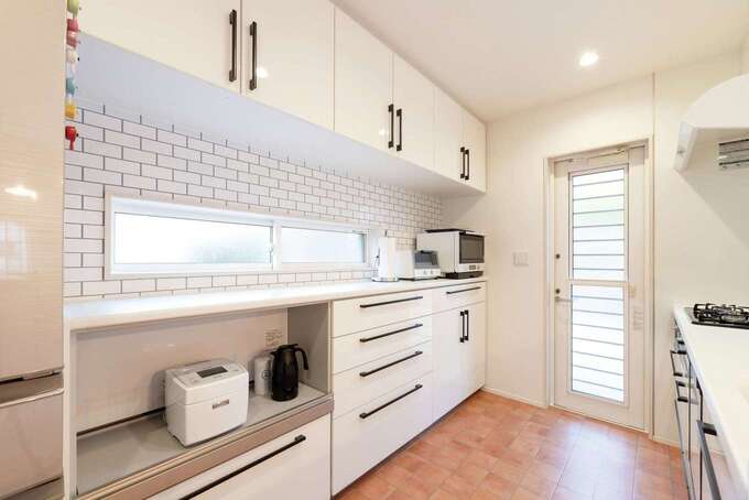 白で統一された明るい北欧風キッチンは、収納力も抜群。背面カウンターに備えた窓からもやわらかな光が入る