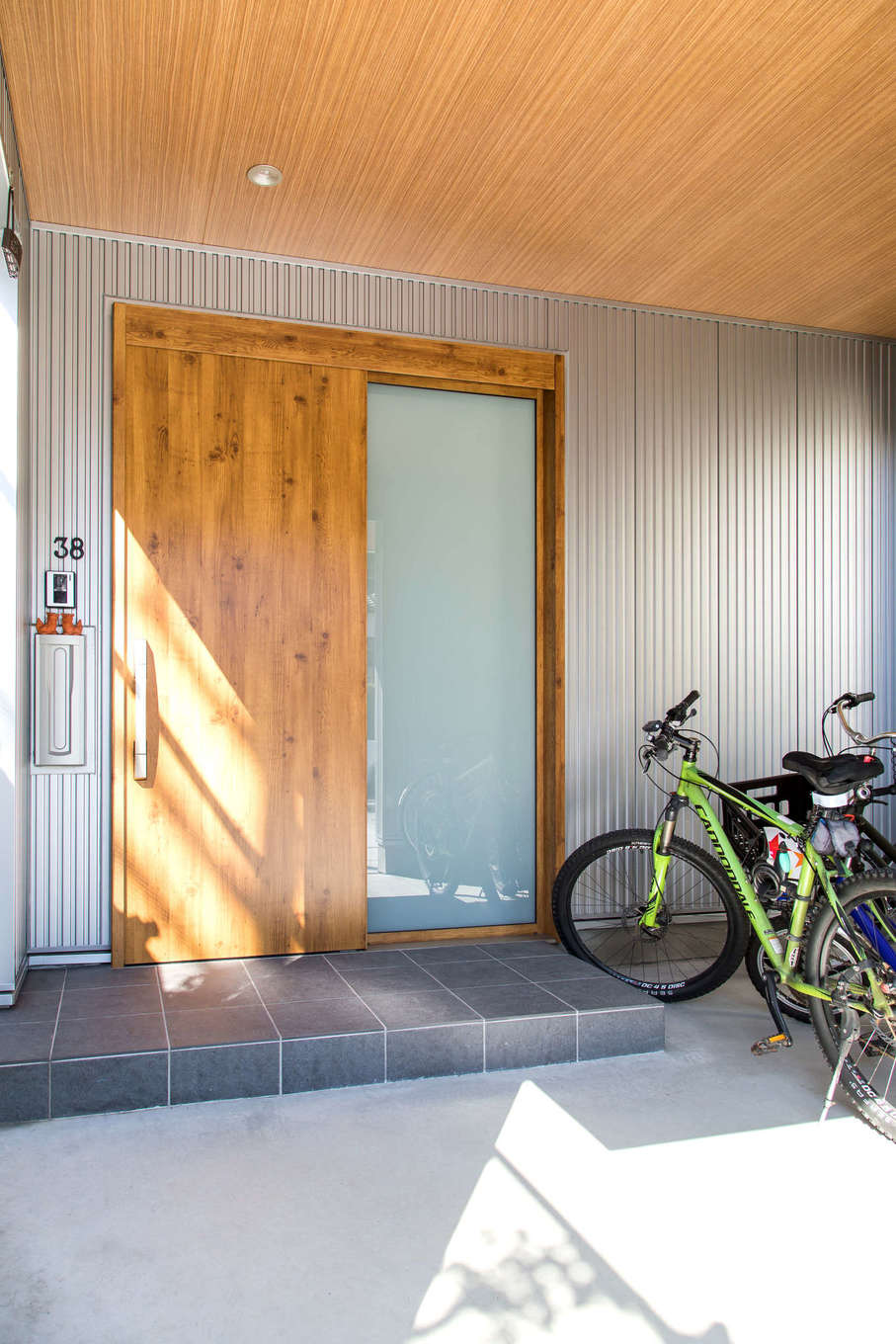 建築システム（狭小住宅専門店）【狭小住宅、間取り、屋上バルコニー】LDKに合わせたことで広くなった玄関の軒先を利用して自転車置き場も確保。外から見えにくく、雨にも濡れないので安心。キャンプ用品などを洗った後も干しておけるゆとりの空間