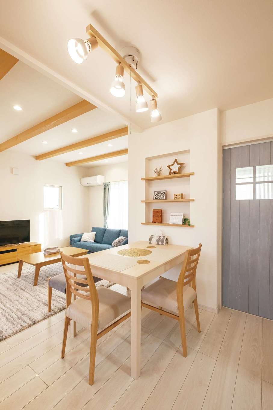 イデキョウホーム【デザイン住宅、省エネ、屋上バルコニー】キッチンを奥にまとめたことで、リビングとキッチンの間にバランスよくダイニングスペースを配置できた。ペールブルーのドアで北欧風のイメージに