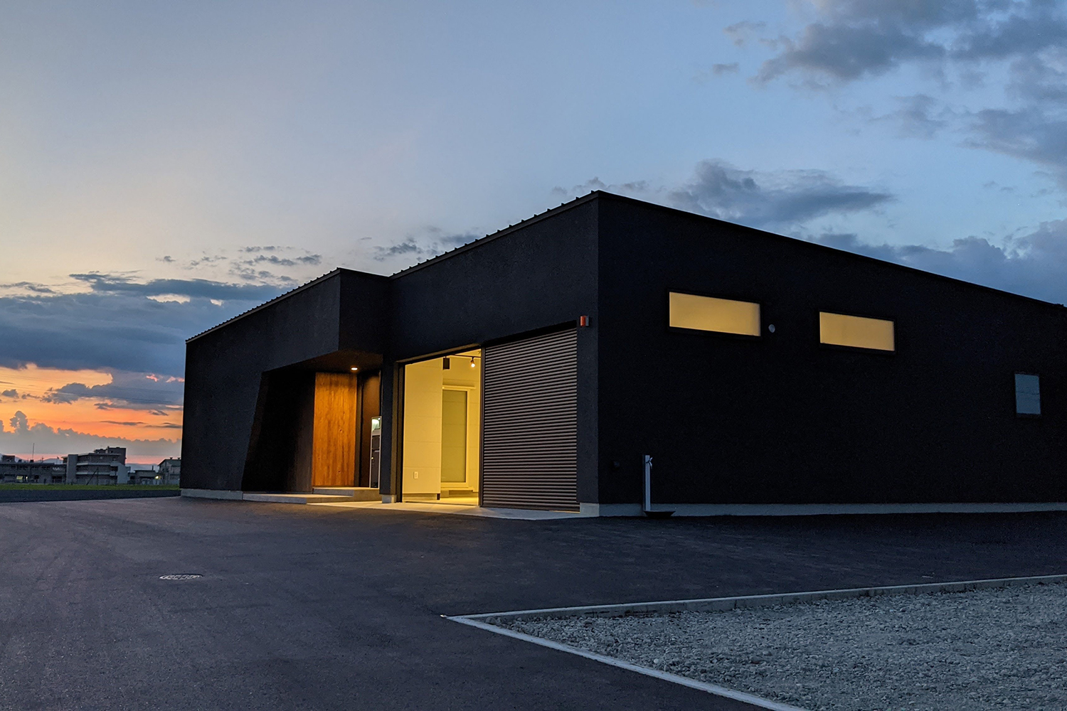 ETERNITY（エタニティ)　SIMPLE NOTE 浜松東【デザイン住宅、平屋、ガレージ】黒い塗壁のシンプルな外観は、夕暮れにも美しく映える。無垢板のアクセント壁や、ガレージからこぼれる光もデザインの一部に