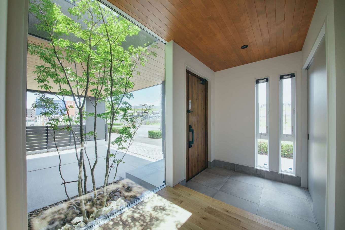 Yamaguchi Design 【磐田市見付1853‐20・モデルハウス】明るく広々とした玄関。ホールにはピクチャーウィンドウを設置。ガレージの車や植栽を室内から眺められる