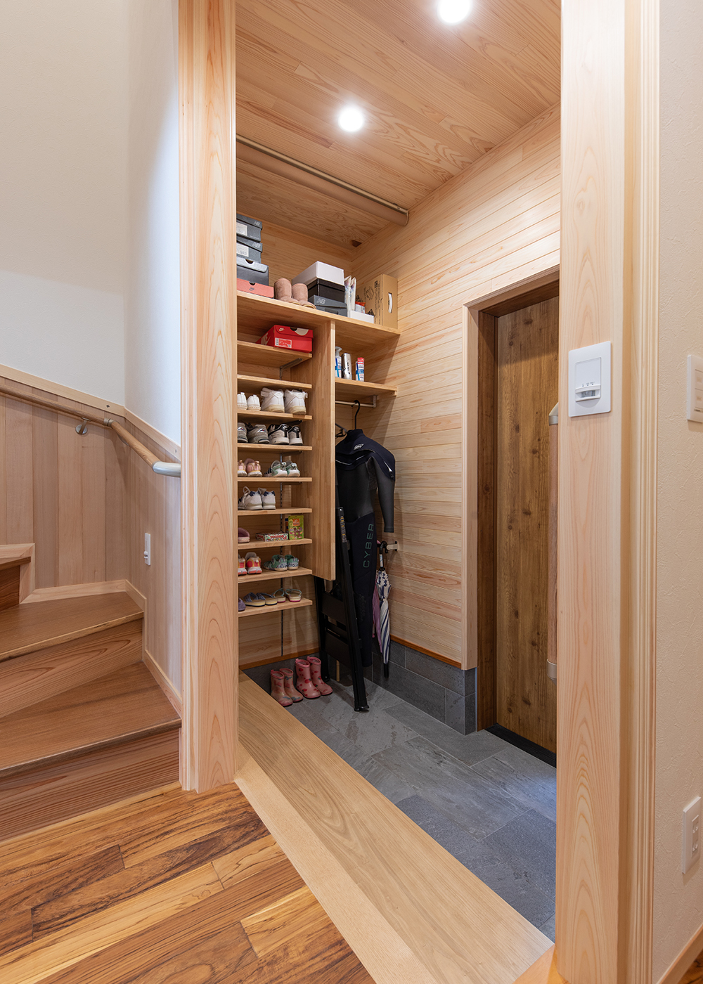 櫻 工務店【自然素材、狭小住宅、間取り】玄関収納は小さな子どもたちも出し入れしやすいオープンスタイル。傘やサーフィンで使うウェットスーツなども掛けられる。来客時はロールスクリーンで目隠し
