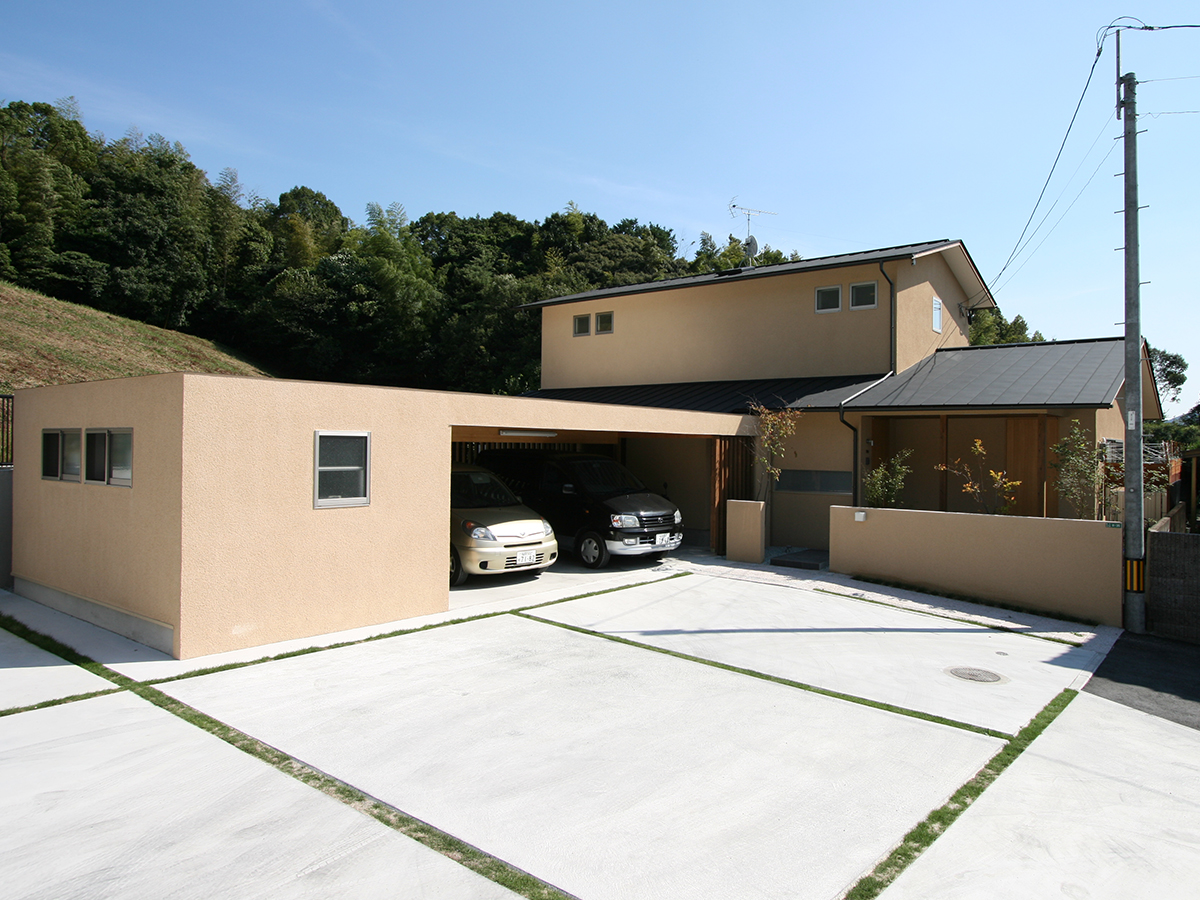 斉藤工務店｜シンプルでモダンなデザインの住宅外観。広い駐車スペースと、統一感のある色調が周囲の緑と調和している。