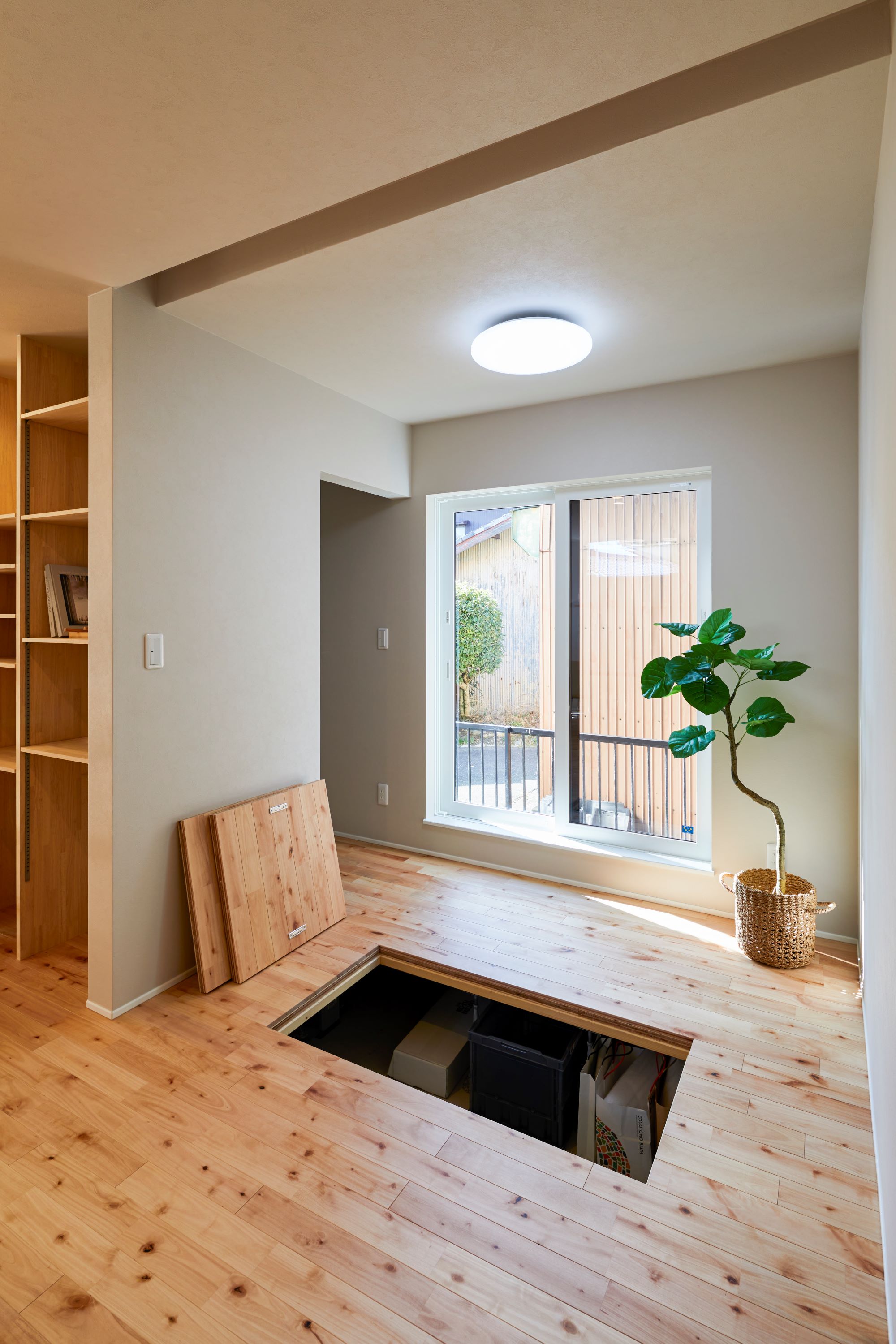GATE（R+house春日井）｜床下収納が施されたフリースペース。明るい窓から自然光が差し込み、植物が心地よいアクセントを加えている。