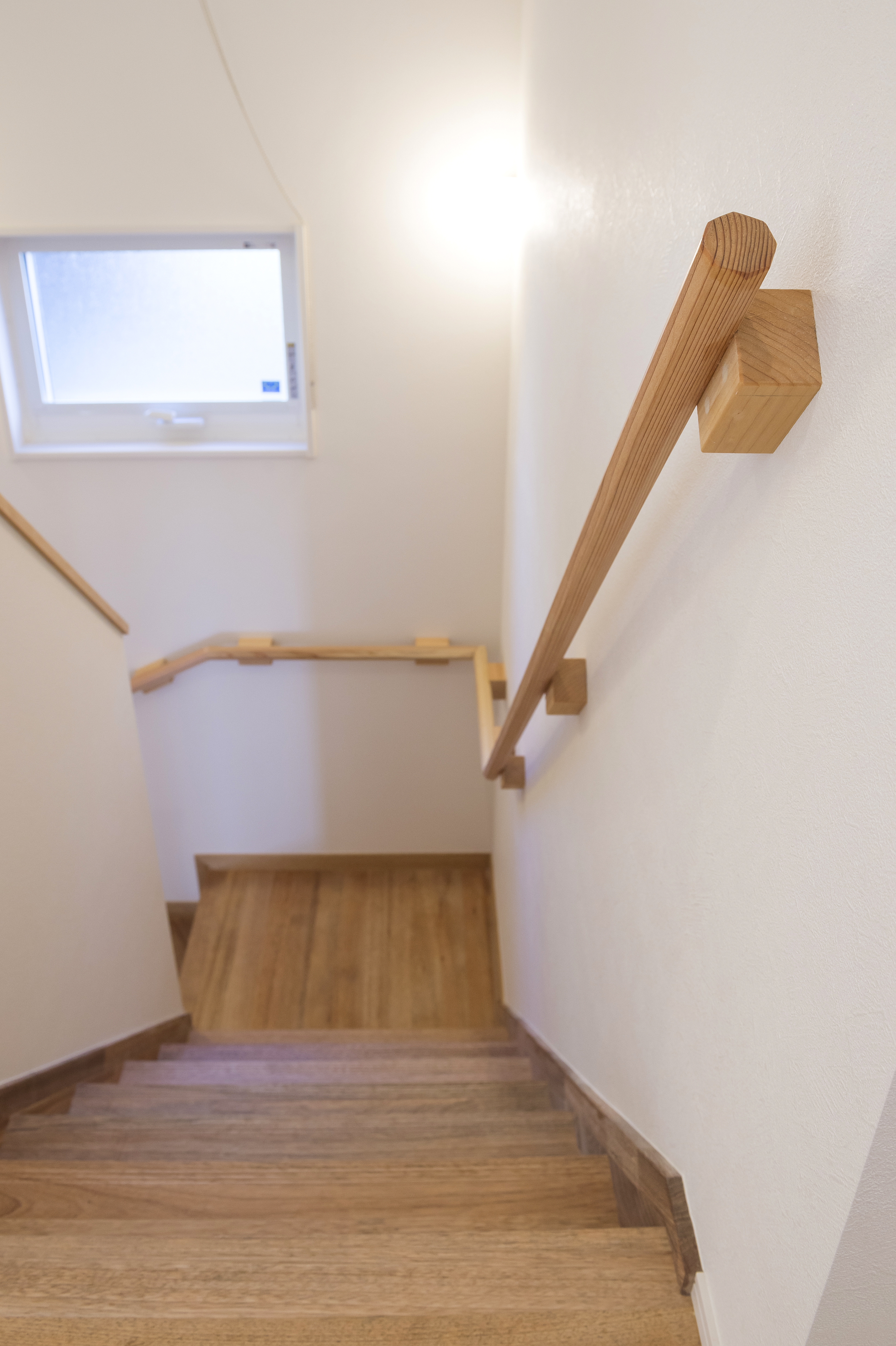 しあわせの住まい一級建築士事務所｜木目調の階段。手すりも木で統一され、暖かみのあるデザイン。明るい窓から自然光が差し込み、快適に移動できる空間。
