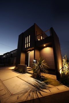 夜間にライトアップされたモダンな外観。洗練されたデザインと植栽が、落ち着いた住まいの雰囲気を醸し出している。