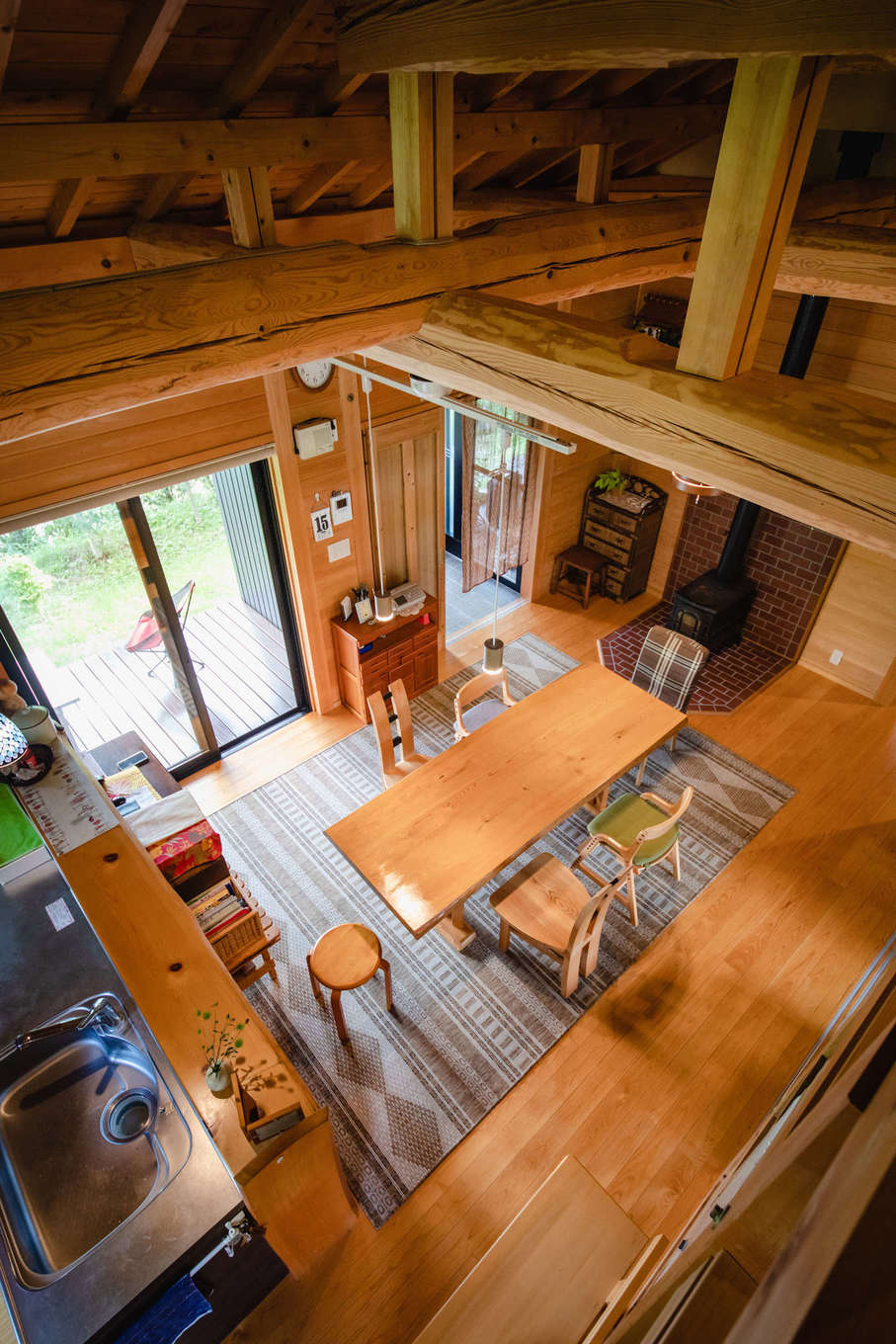 安形【自然素材、夫婦で暮らす、平屋】小屋裏から眺めたダイニングキッチン。毎年、初冬に入ると薪ストーブを焚いて過ごすのが日課に。「薪ストーブのおかげで家中が暖まります。揺らめく炎を眺めながらゆったりと過ごす時間もまた愉しいものですよ」とご主人