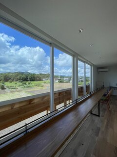 大きな窓から景色が広がる明るい廊下。自然光がたっぷり差し込む空間で、開放的な雰囲気が感じられる。