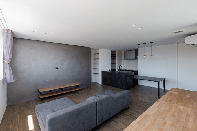 モダンでシンプルなデザインのLDK。広々とした空間にダークトーンのソファとカウンターテーブルが配置され、落ち着いた雰囲気を演出している。