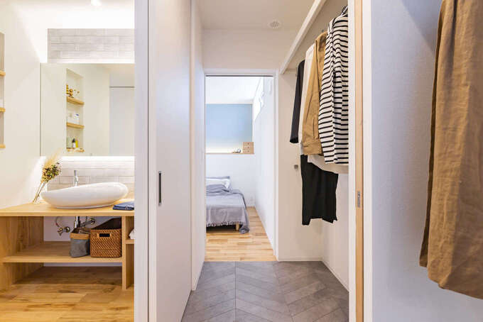 寝室と水回りを結ぶウォークスルークローゼット。洗面スペースは浴室と独立させ、ランドリーと仕切ることもできるので、来客時に生活感をすっぽりと隠すことができる。手前のランドリーに干した衣類が乾いたら、そのままクローゼットにハンガーを掛け替えるだけで済むので、家事も楽々