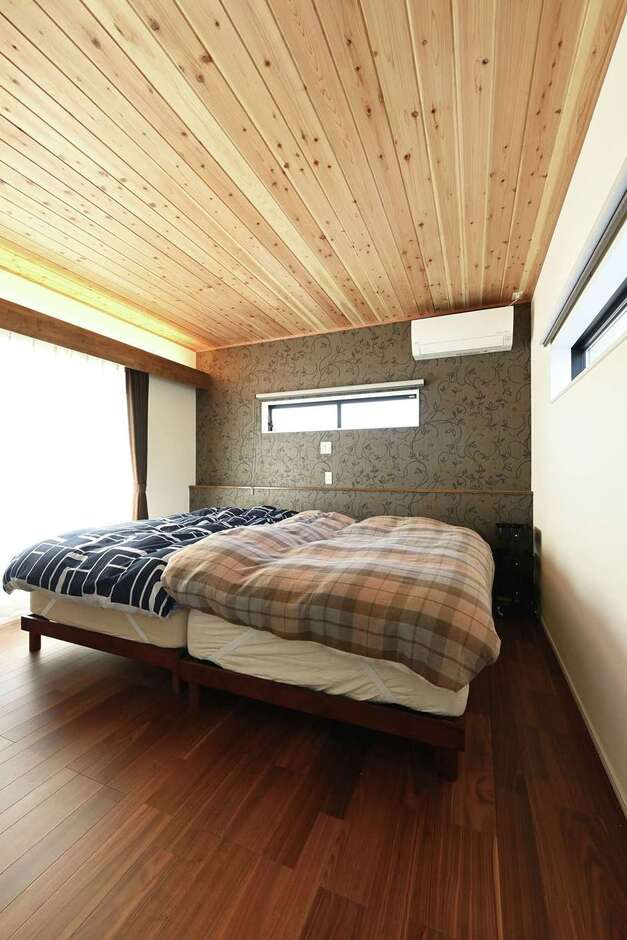 1階の和室と同じく、天井に杉板を貼った主寝室。グレーのアクセントクロスと間接照明に癒やされる