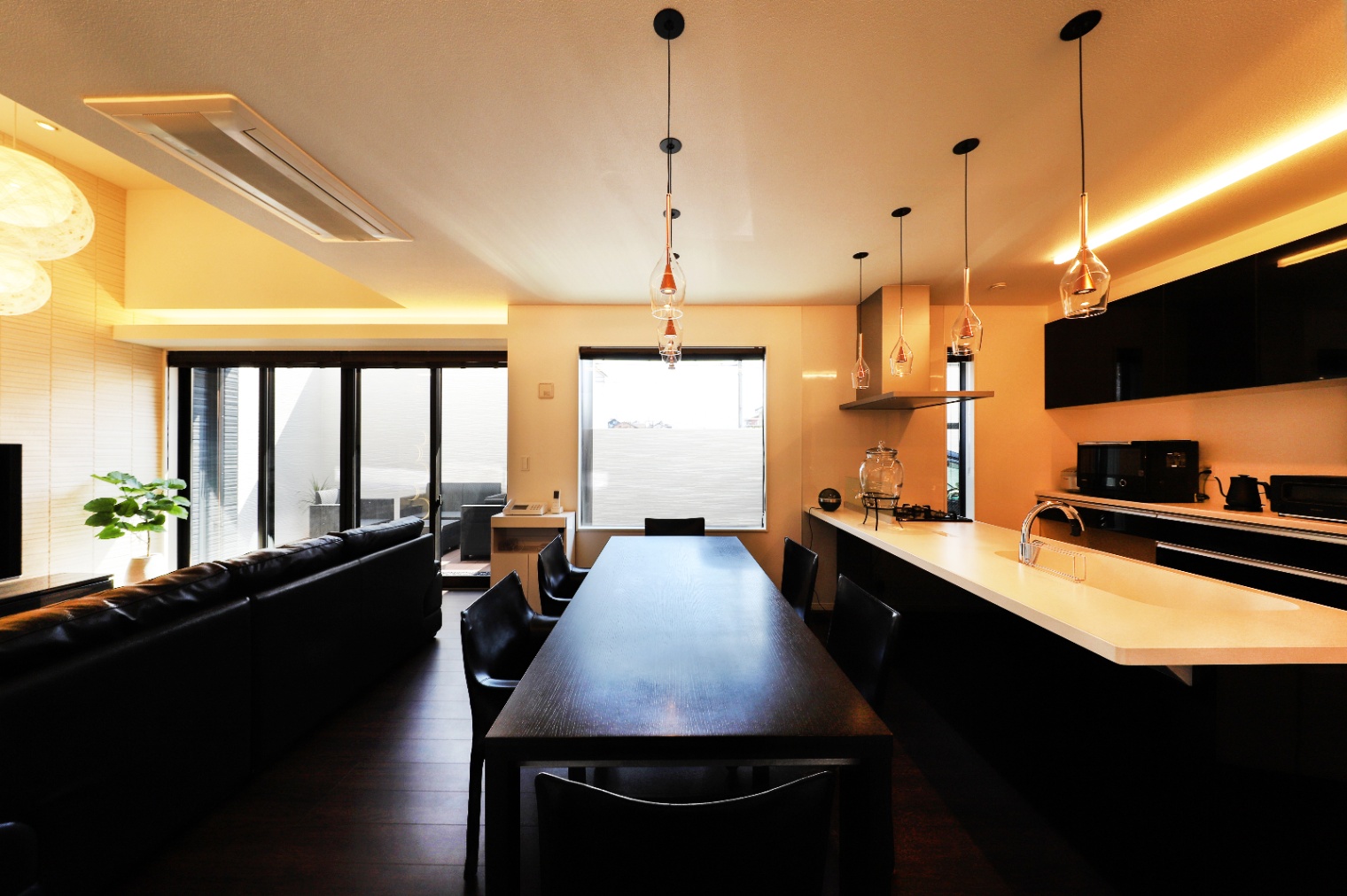 アイダ設計　｜広々としたLDKの空間。スタイリッシュなキッチンと、ダイニングテーブルが一体となったデザインが、開放感をもたらしている。