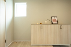 明るい玄関スペース。シンプルなデザインの収納が壁に沿って配置され、ナチュラルな木目が落ち着いた雰囲気を演出している。