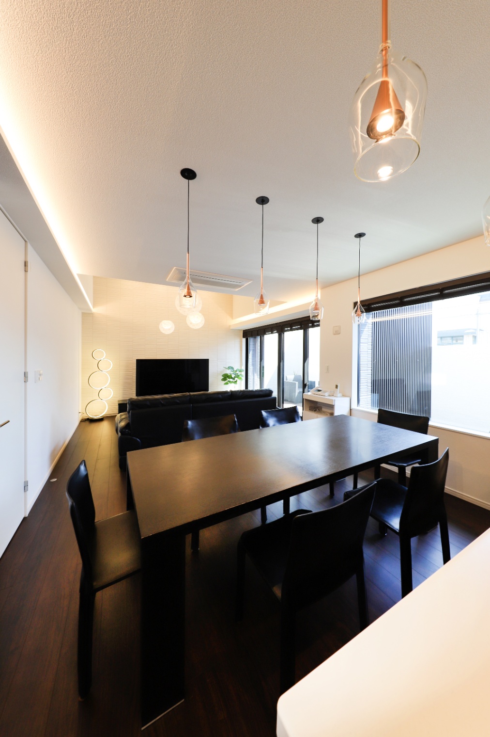 アイダ設計　｜モダンなダイニングルーム。シックな木製のテーブルと椅子が落ち着いた雰囲気を演出。ペンダントライトが空間に温かさを添えている。
