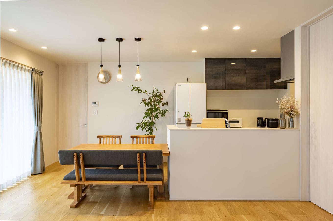 AQURA HOME（アキュラホーム）【デザイン住宅、収納力、間取り】キッチンと横並びのストレートダイニングは、配膳も片付けもしやすくて便利。キッチンの腰壁が高く手元が見えないので、不意の来客時も安心