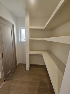 壁一面に棚が設置された広々としたパントリー。食材やキッチン雑貨をすっきりと収納できる実用的なスペースである。