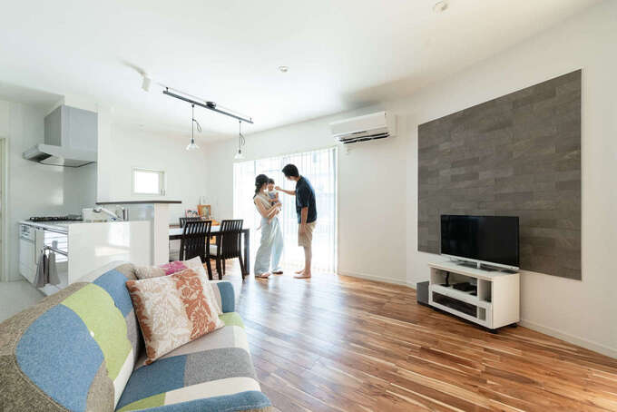 23畳のLDK。白い壁にアカシアの床とグレーのエコカラットが映える。家族がどこにいても様子が見える位置に対面キッチンを配置した