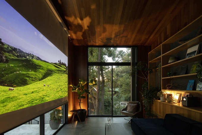 壁一面に大きなスクリーンが設置されたシアタールーム。木製のインテリアと間接照明が温かい雰囲気を醸し出しており、リラックスできる空間となっている。