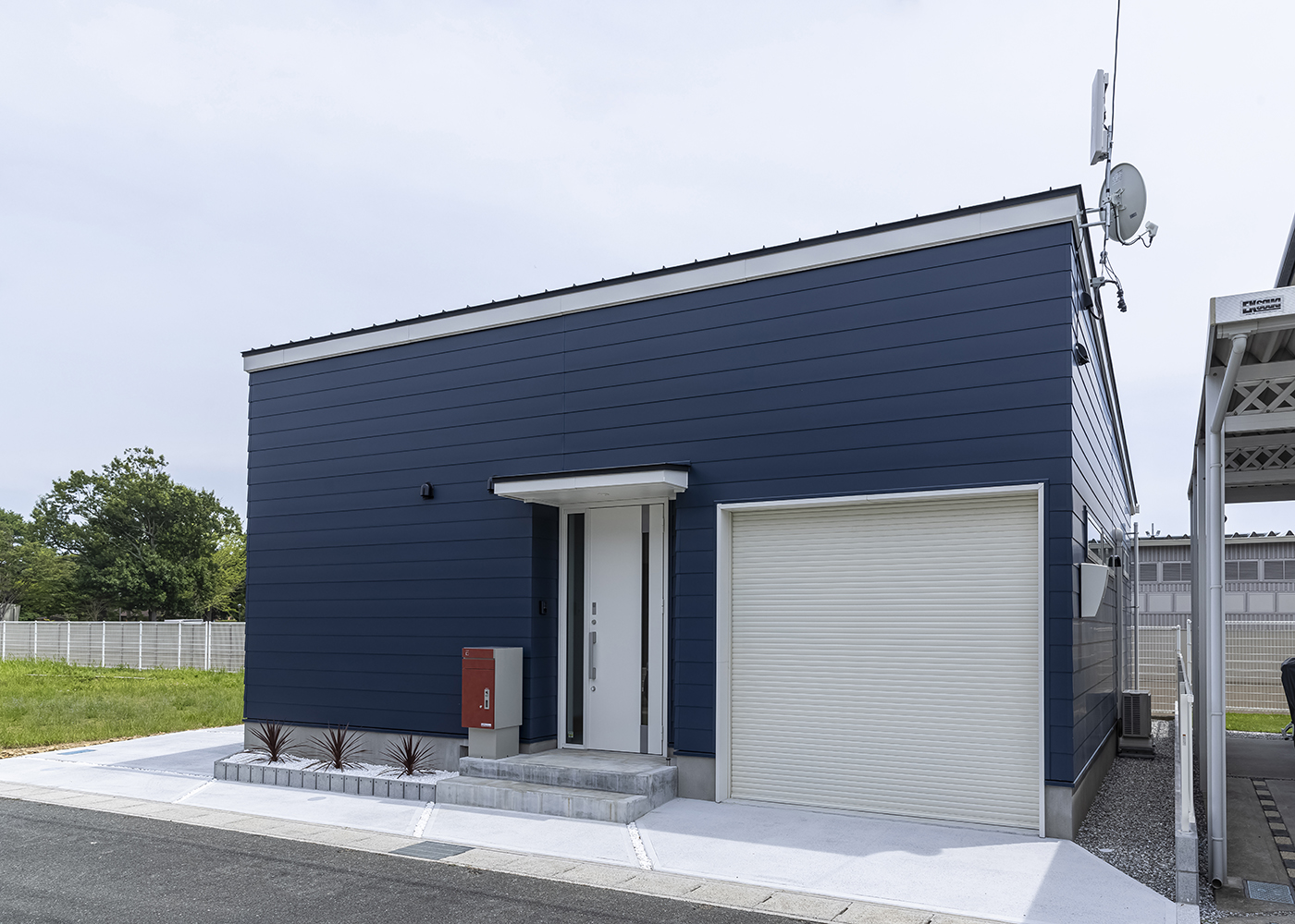 カナメクラフト（かなめ創建）【自然素材、建築家、平屋】ブルーの外壁に宅配ボックスの赤が映える