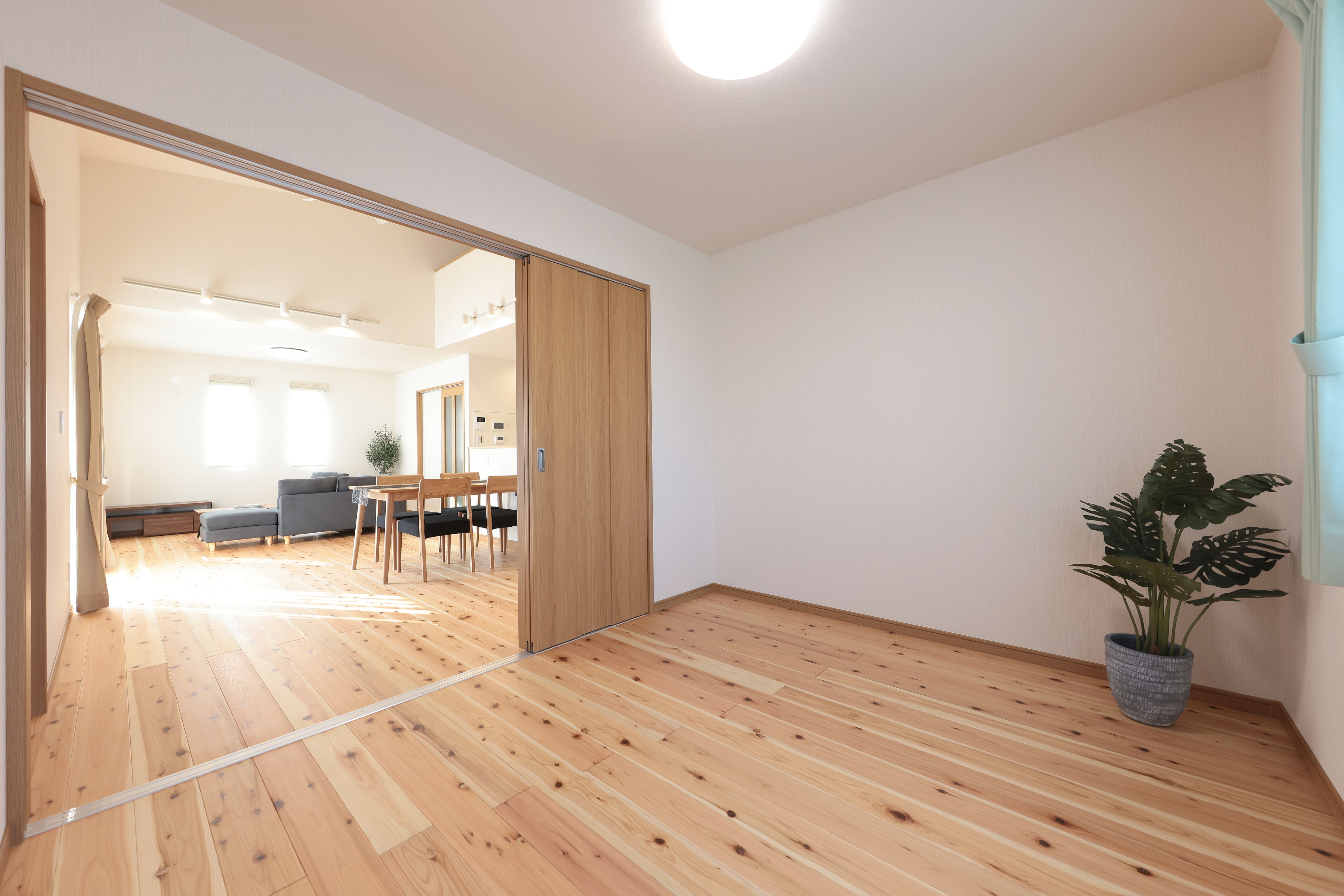 サンポウ｜木製フローリングが広がる明るい居室。大きな窓から自然光が差し込み、開放感を演出している。隣接するリビングが見渡せるため、家族の気配を感じながら過ごせる空間。