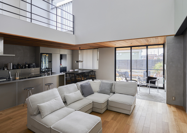 大きな吹き抜けが開放感をもたらすLDK。オークの床にヒートポンプ式の床暖房を採用したため、これだけ広い空間でも冬に暖かく過ごすことができる。リビングの背面にはキッチンスペースが設けてあり、キッチンから室内全体が見渡せる