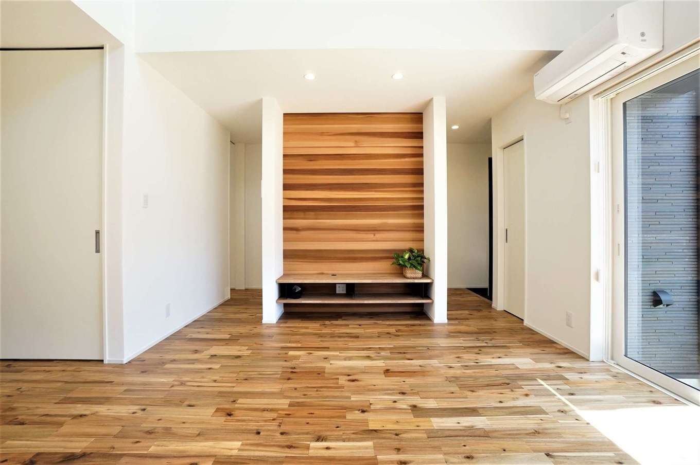 RIKYU 一級建築士事務所【デザイン住宅、間取り、建築家】造作のテレビボードはレッドシダーを使用。玄関からこのボードの裏を通ってサニタリー、将来の親御さんの部屋へとアクセスすることができる。つながりを持たせながら、緩やかにゾーンニングした「裏動線」に建築家らしさを感じる