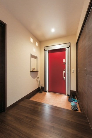 断熱、電気錠の最新式玄関ドア。家全体がシンプルな分、ビビッドな赤がアクセントになっている。玄関ホールにはリビング側のガラスブロックから光が差し込む