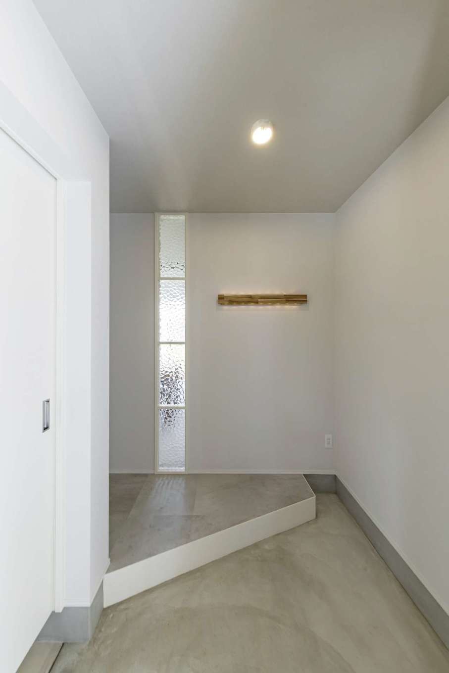 Gate air house/阿部住宅【デザイン住宅、間取り、インテリア】モルタル仕上げの玄関ホール。天井、壁を白で統一したことと、框を斜めに切ったことで空間をより明るく、広く見せている。収納力も充実