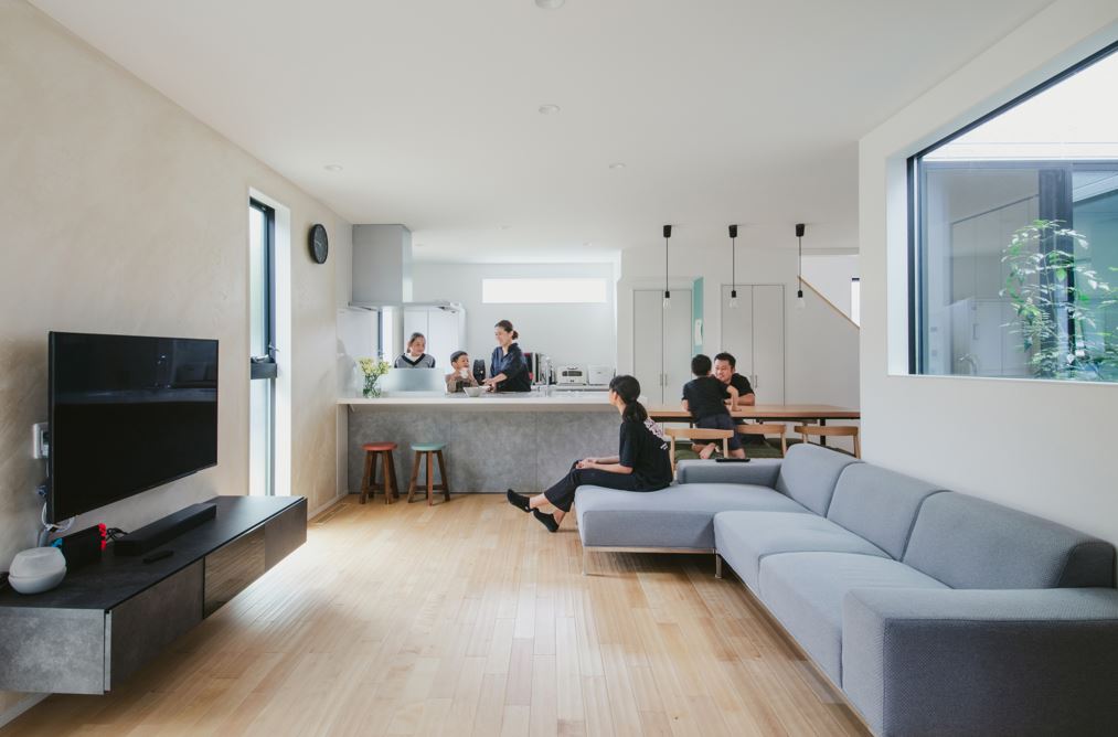 nattoku住宅【デザイン住宅、子育て、収納力】家族がいつも集まる開放感あふれるLDK。凹凸感が足裏に心地よく伝わる無垢の床は『nattoku住宅』オリジナルの「ジョージⅡ」。坪庭からの光が漆喰の白い壁に反射して、空間がより明るくなる。テレビの背面にイタリア漆喰の「ユーロスタッコ」を塗ってアクセントに