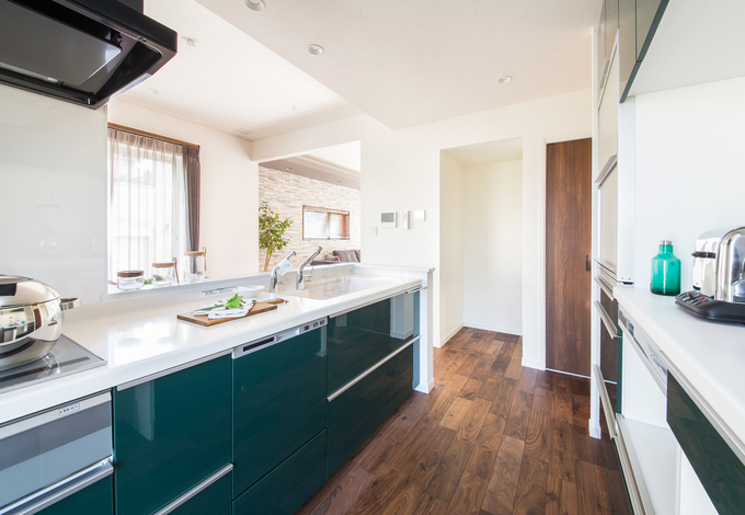鏡面仕上げのダークグリーンな扉のシステムキッチン。カップボードのほかにパントリーもあるため、いつでもスッキリとしたキッチンが目指せる