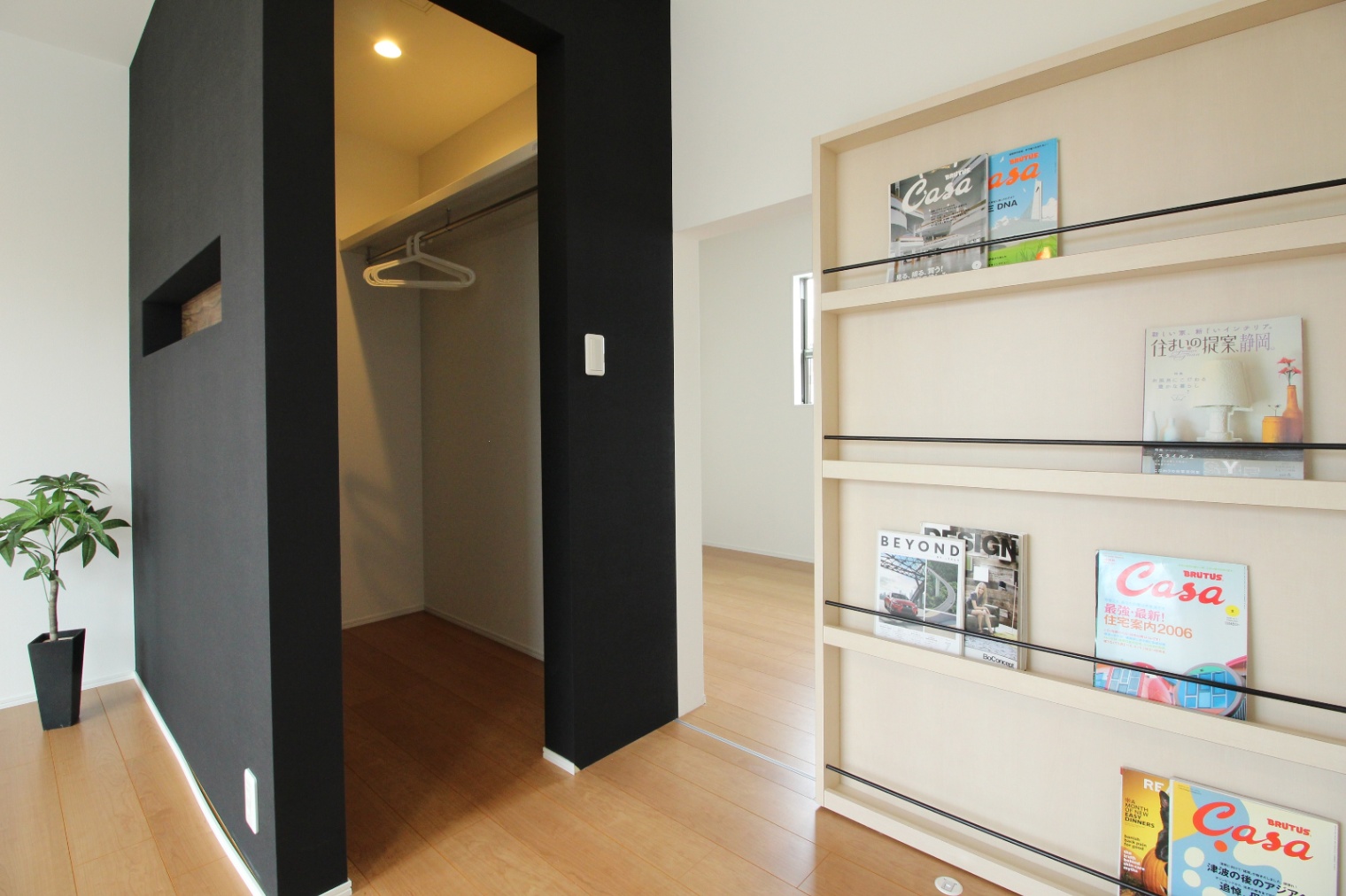 小野田産業～designers house project～｜スタイリッシュなウォークインクローゼット。黒い壁と本棚がアクセントになり、収納力だけでなくデザイン性も意識されている。