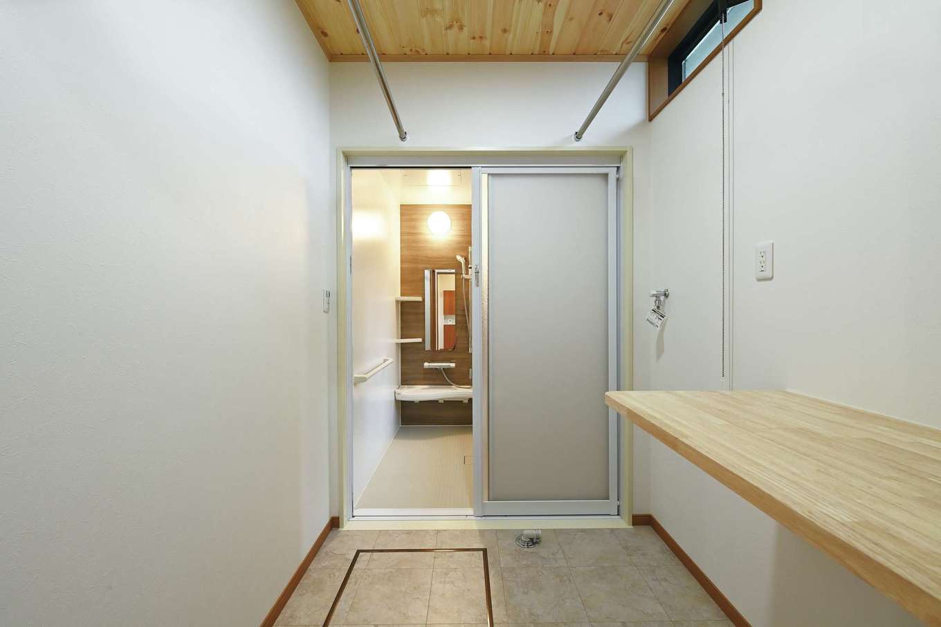 住まいるコーポレーション【収納力、趣味、自然素材】室内干しの竿を2本用意し、洗濯物がたっぷり干せるスペースを確保したランドリー兼脱衣室。家事カウンターでアイロンがけをしたり、洗濯物をたたんだりもできる