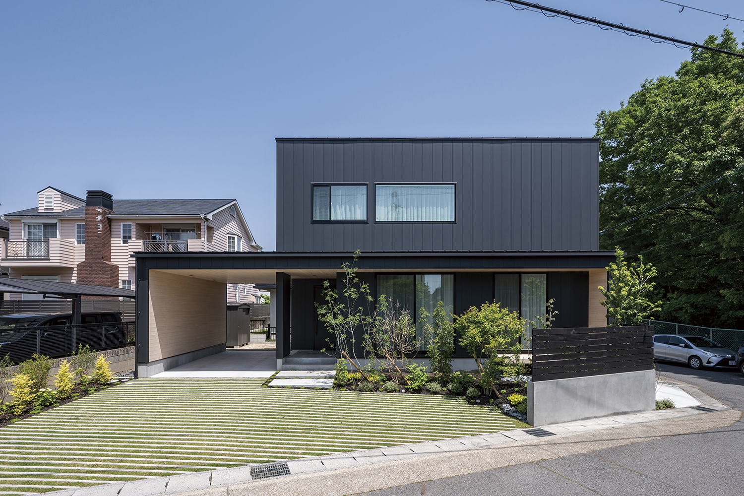 アールギャラリー（アールプランナー）【デザイン住宅、自然素材、建築家】土地の間口の広さを活かしてオープン外構を採用。植栽の緑に、黒の外観と軒天井に配した天然木、そして白基調の室内へとつながる色彩のバランスが素敵だ