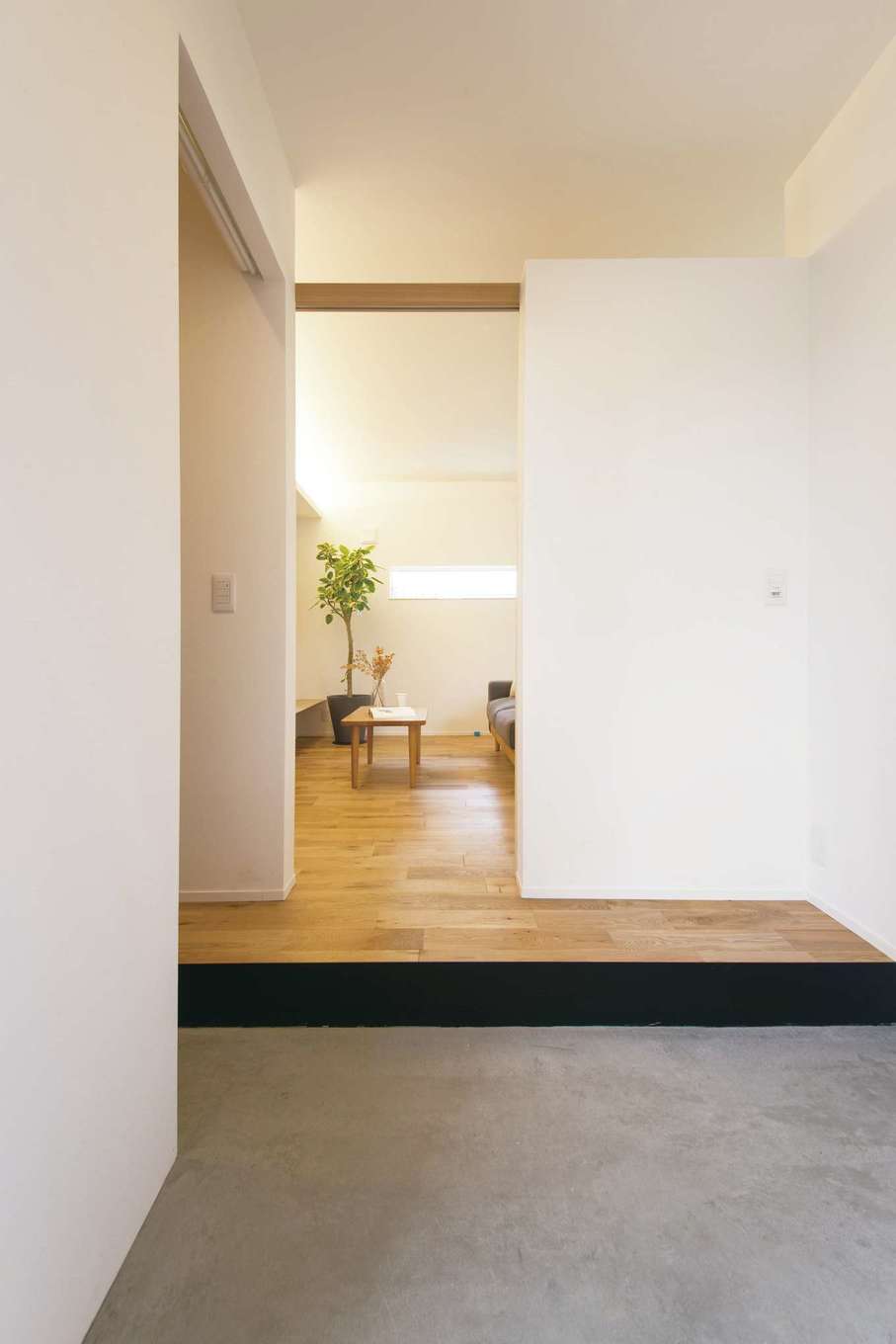 ARRCH アーチ【狭小住宅、建築家、平屋】玄関とLDKの境の壁は上部をオープンにしてあり、LDKの灯りが玄関にもこぼれてくる。左手の奥はシューズクローク