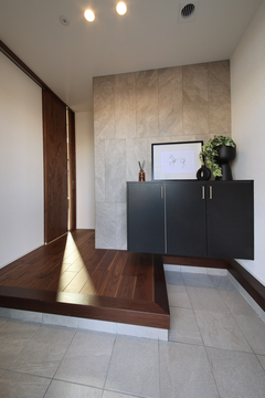 モダンで落ち着いた印象を与える玄関ホール。壁のアートと観葉植物が温かみを添え、来訪者を迎え入れる空間となっている。