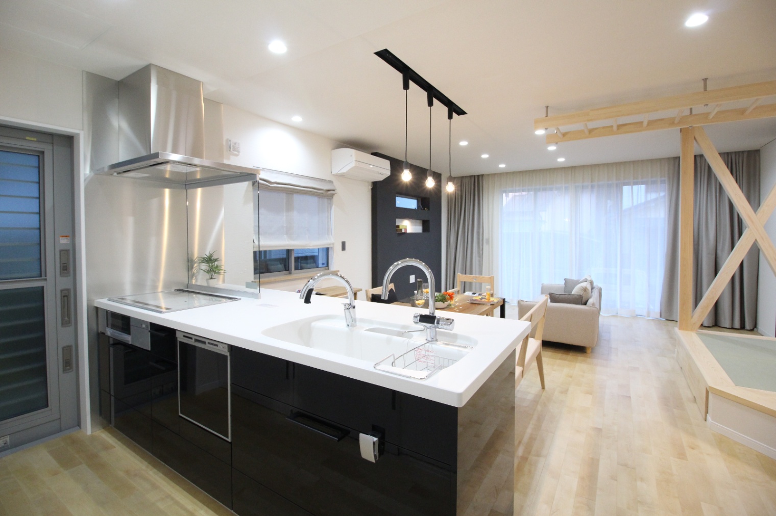 小野田産業～designers house project～｜広々としたLDKの空間。オープンキッチンとリビングがつながり、家族団らんの時間を楽しめる設計。シンプルでモダンな照明がアクセントになっている。